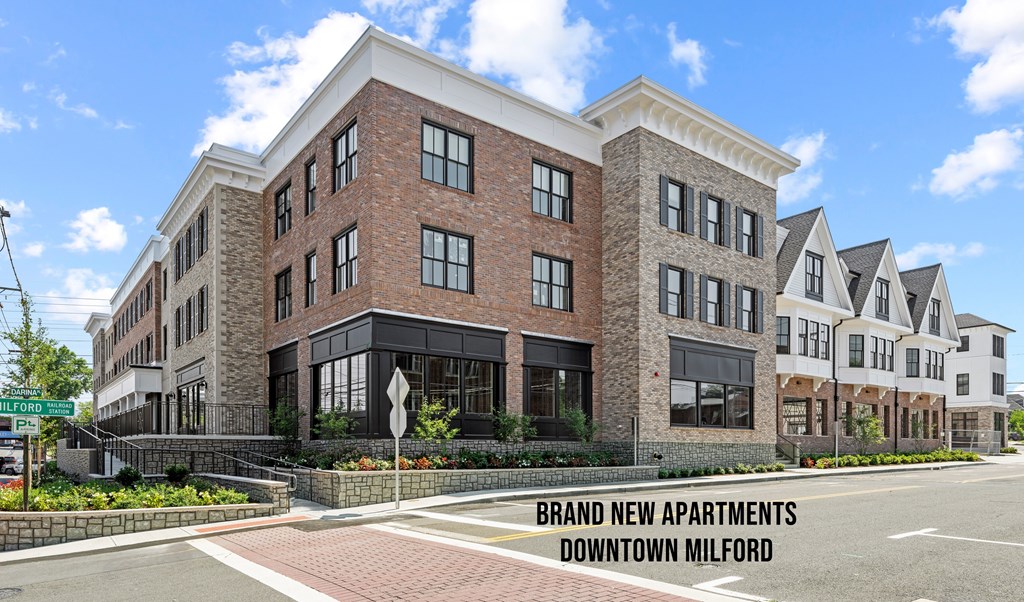 A large brick building with a sign that says "Brand New Apartments Downtown Milford".