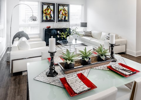 A modern dining room with a glass table and white chairs.