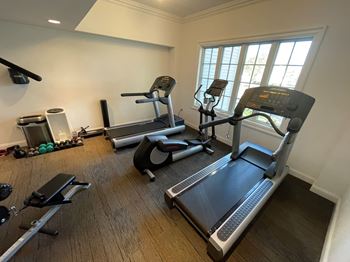 A gym with a treadmill, elliptical trainer, and other exercise equipment.
