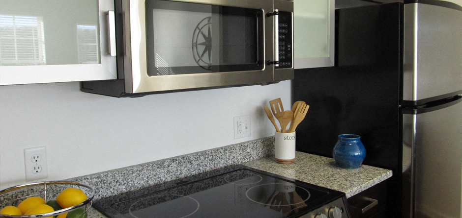 A kitchen with a black stove top and a black refrigerator.