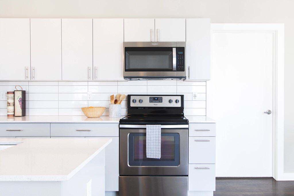 A modern kitchen with a black oven and white cabinets.