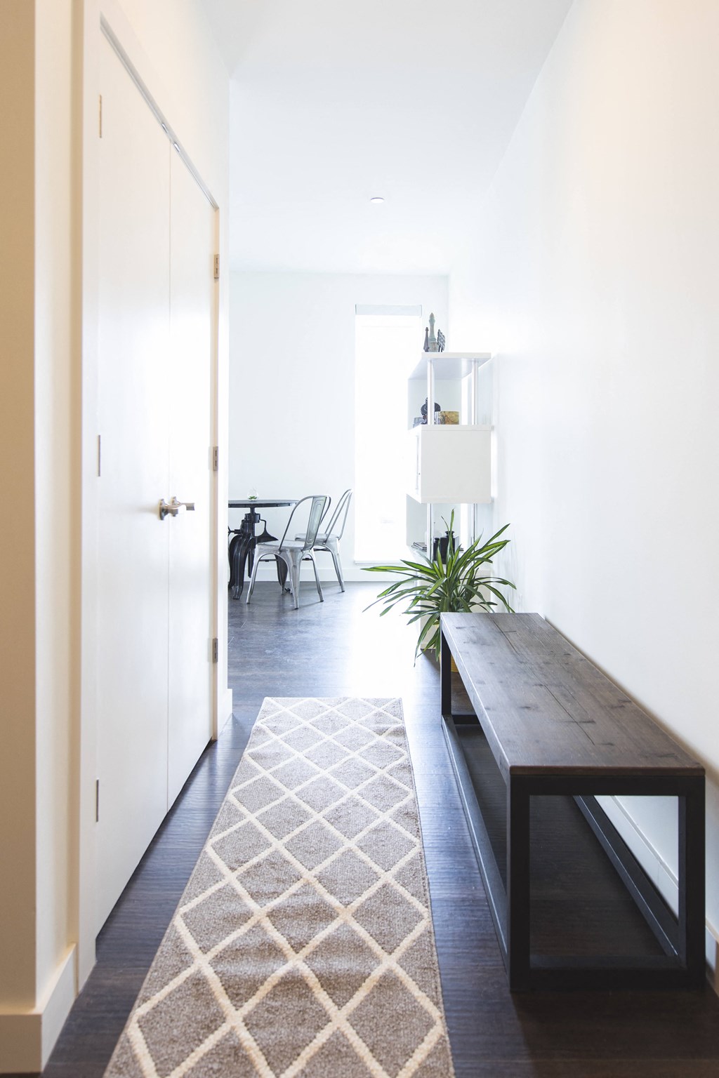 A long hallway with a bench and a rug.