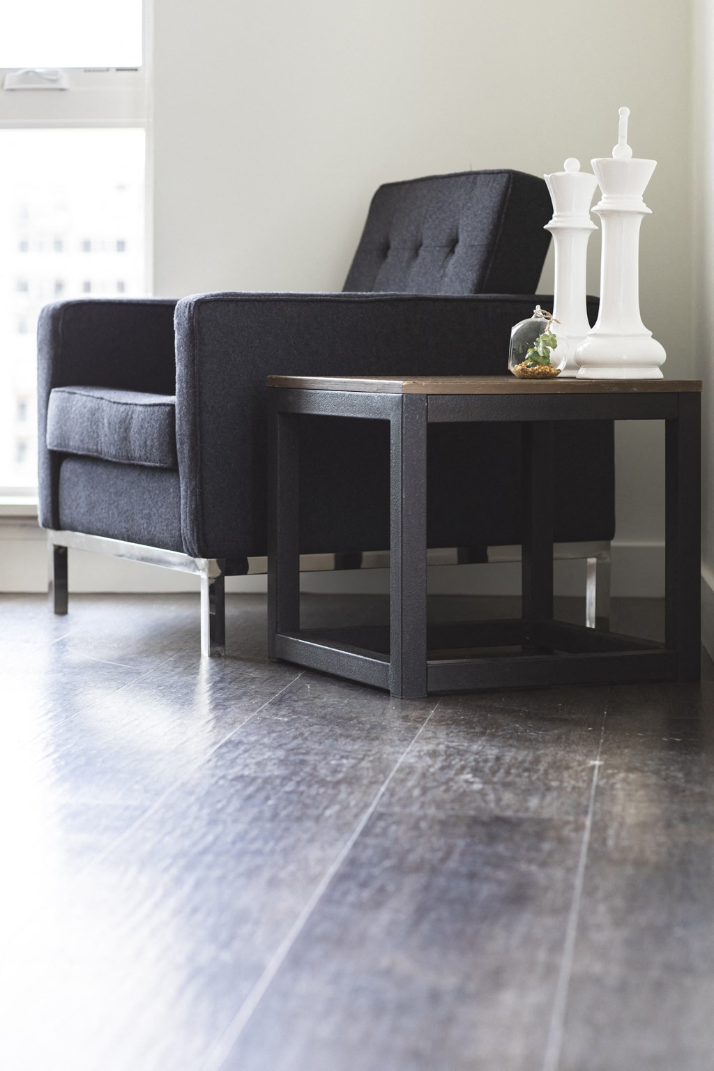 A black chair and table with a white vase on it.