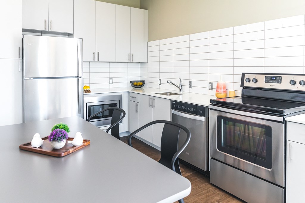 A modern kitchen with a refrigerator, oven, and microwave.