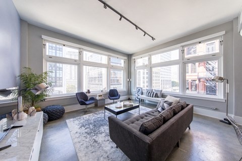 a living room with a couch and chairs in front of a wall of windows