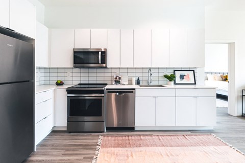 A modern kitchen with a black fridge, stainless steel oven and microwave above the stove.