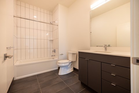 A white toilet sits in a bathroom with a white tiled shower.