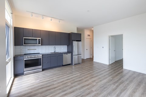 A modern kitchen with wooden floors and stainless steel appliances.