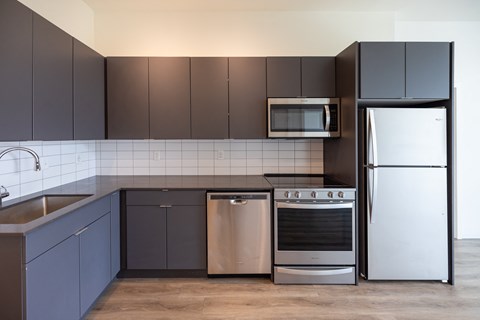 A modern kitchen with dark brown cabinets and stainless steel appliances.