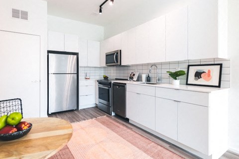 A kitchen with white cabinets and a black fridge.