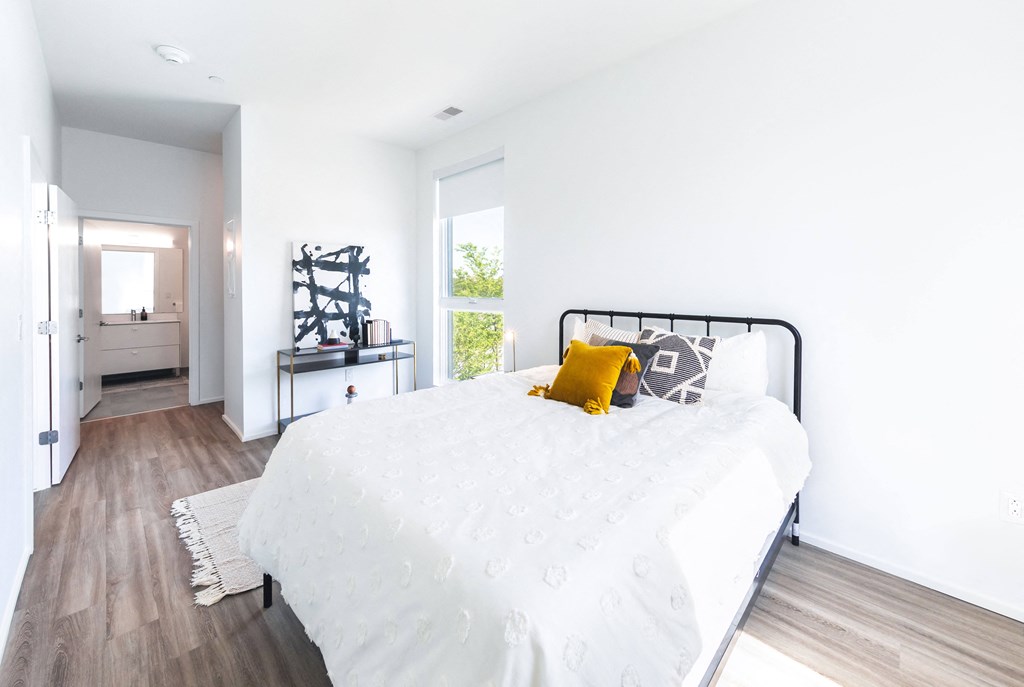 A bedroom with a white bed and a yellow pillow.