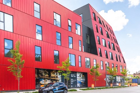 A red building with black windows and a black car parked in front.