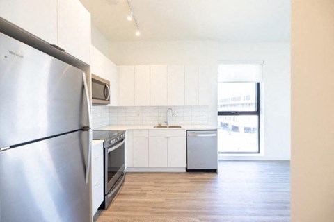 A kitchen with a stainless steel refrigerator and white cabinets.