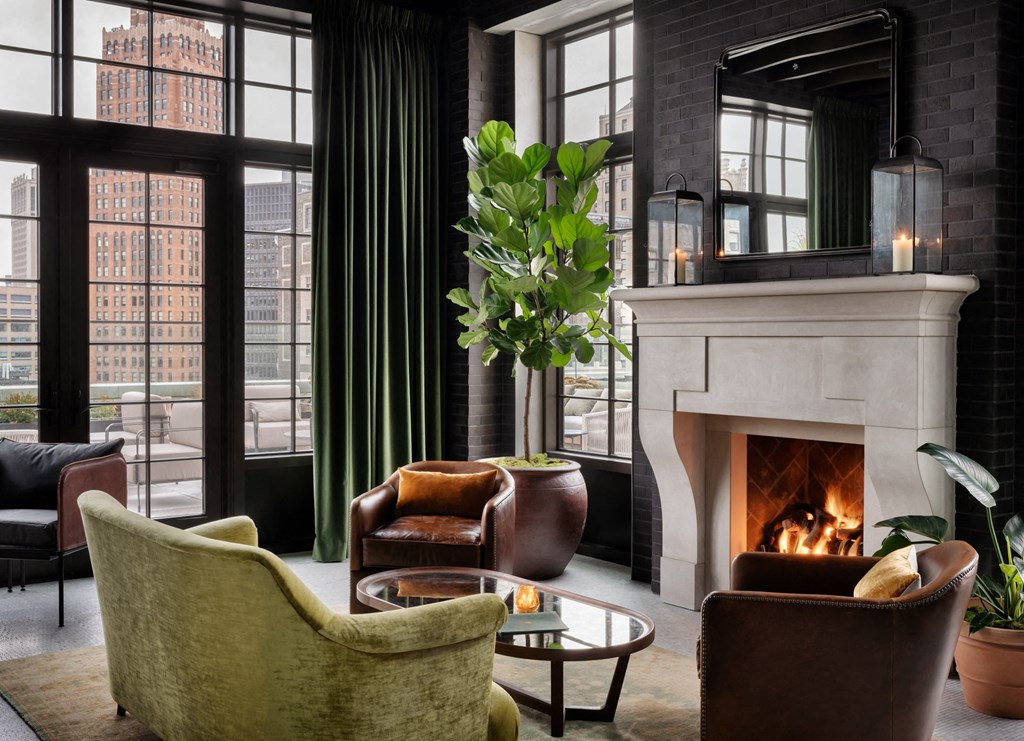 a living room with furniture and a fireplace      and large windows at Book Tower, Detroit, MI