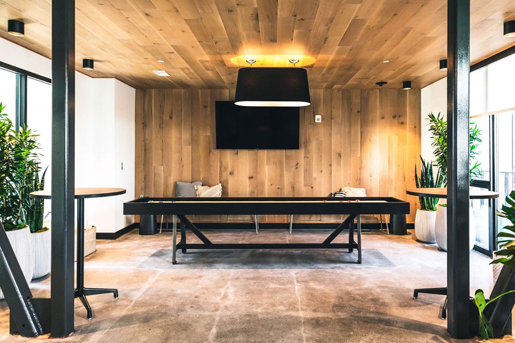 A conference room with a long table and a flat screen TV mounted on the wall.