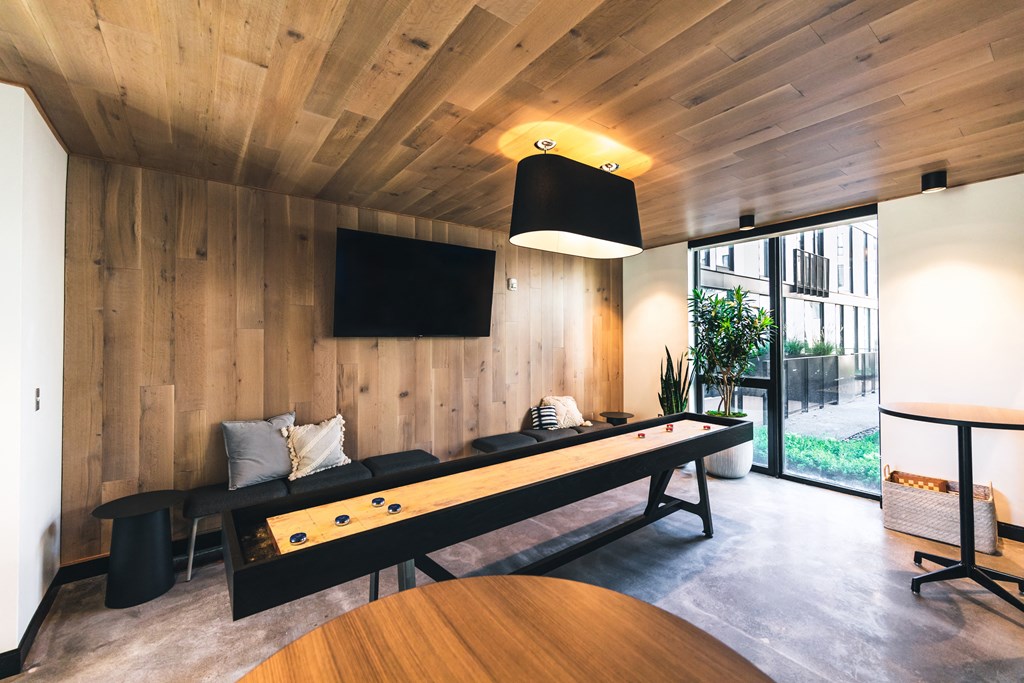 A room with a long black table and a television mounted on the wall.