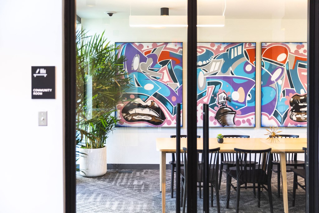 A room with a table and chairs and a painting on the wall.