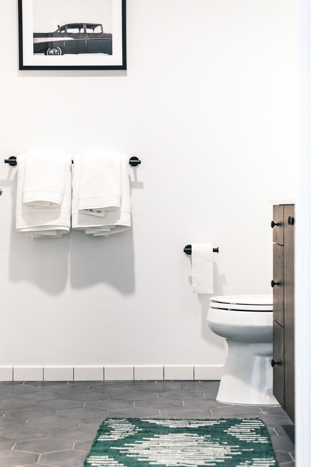 a bathroom with white towels and a green and white rug
