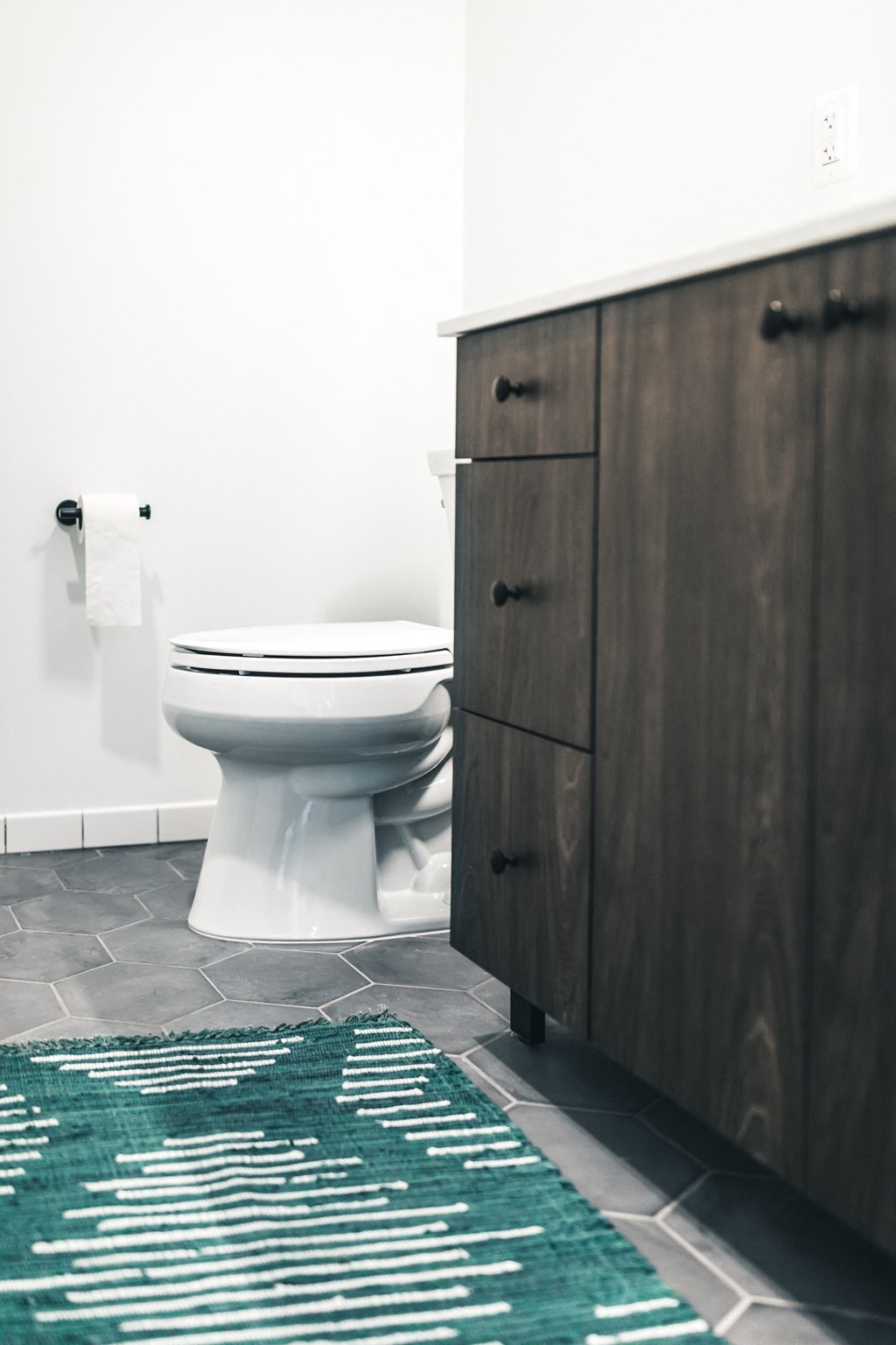 a bathroom with a white toilet next to a wooden cabinet