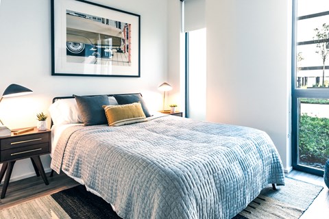 A bedroom with a large bed and a framed picture on the wall.