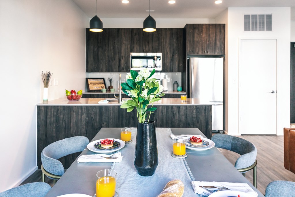 a dining area with a table and chairs and a kitchen in the background