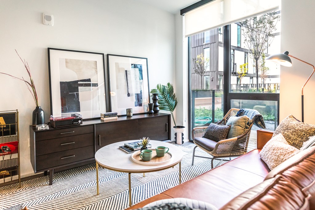 a living room with a brown leather couch and a large window