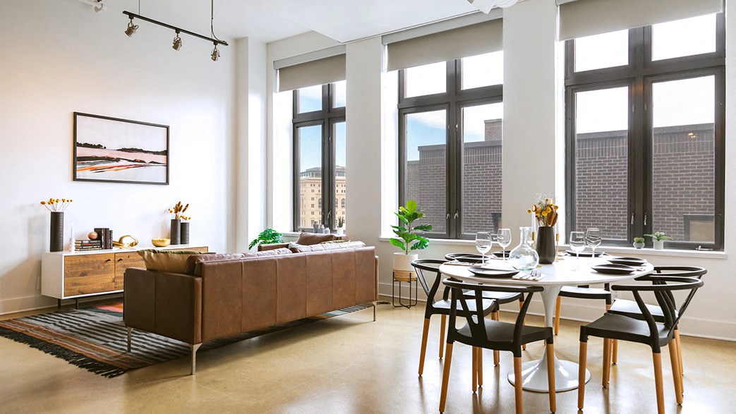 a living room with a table and a couch in front of windows