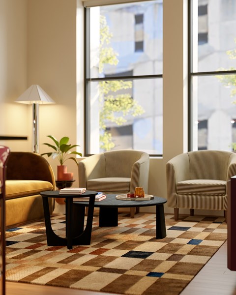 A living room with a brown and white checkered rug and a yellow chair.