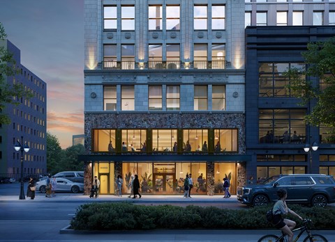 An exterior rendering of The Belle at night with a glass facade and people walking around in front.