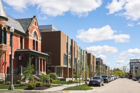a row of townhomes on a street with cars parked on the side of the road