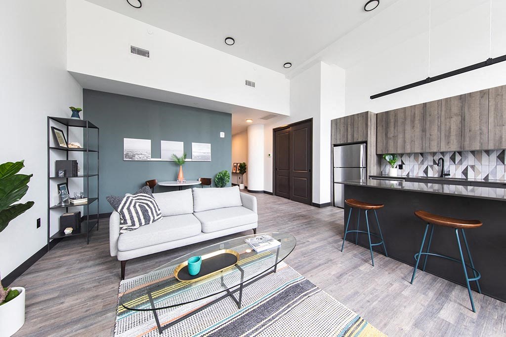 Modern living room and kitchen area with island and bar stool seating at The May.