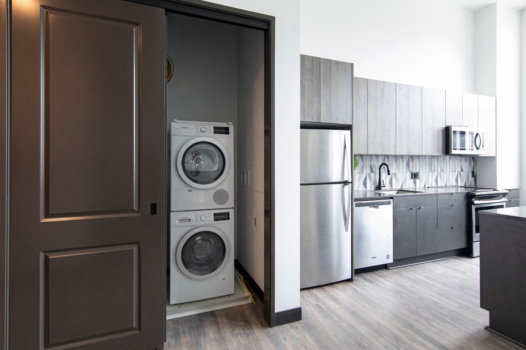 Fully equipped kitchen with stainless steel appliances includes frost-free refrigerator, electric range stove, and dishwasher, at The May.