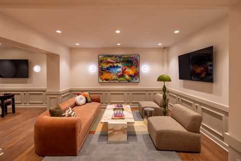 A living room with a brown couch, a coffee table, and a painting on the wall.