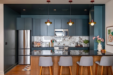 A kitchen with dark blue cabinets and a marble backsplash.