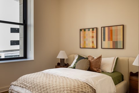 A bedroom at The Belle with a bed, two lamps, and two pictures on the wall.