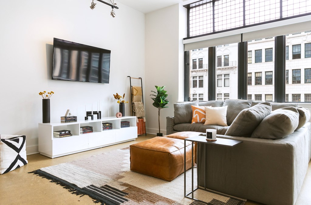 a living room with a large window and a tv on the wall at The Ferguson Apartments, Detroit, 48226