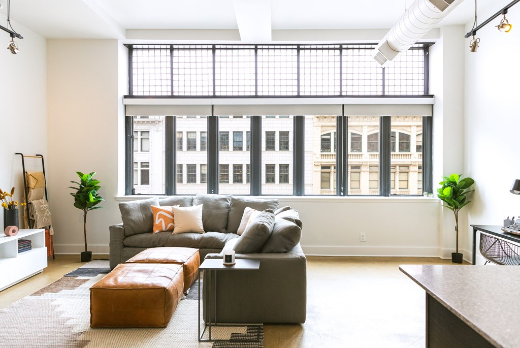 a living room with a couch and a coffee table in front of a large window at The Ferguson Apartments, Michigan