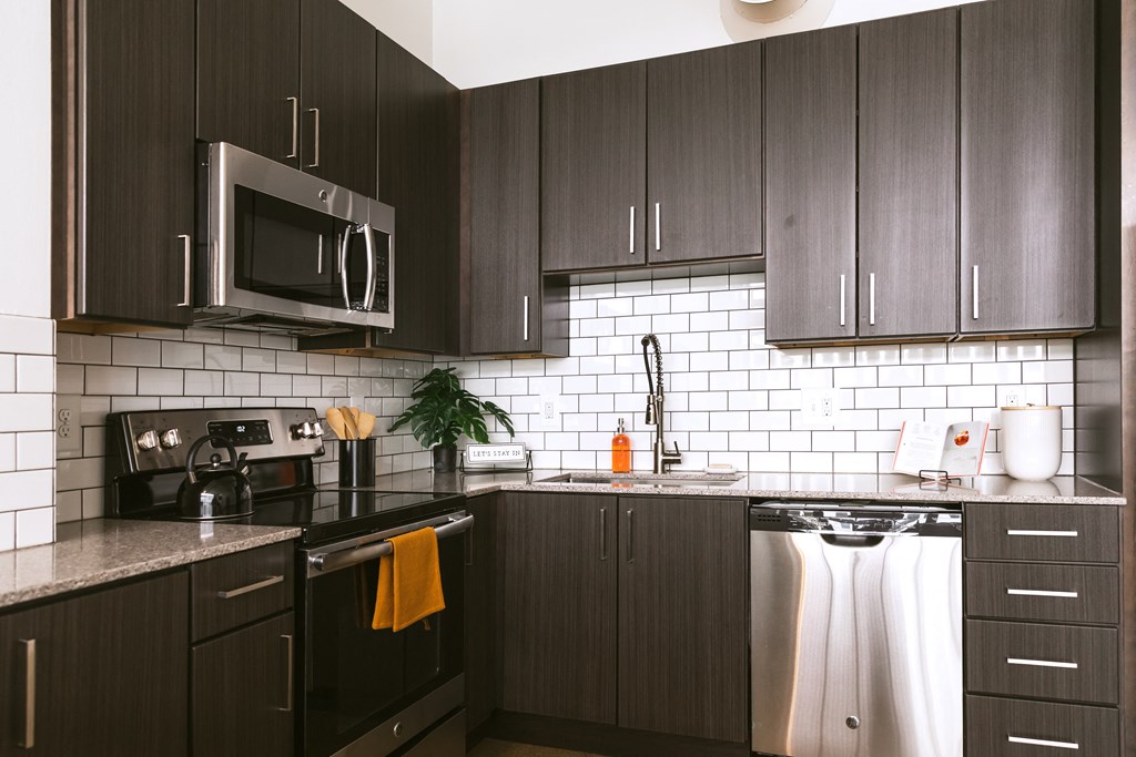 a kitchen with dark cabinets and white tile at The Ferguson Apartments, Michigan