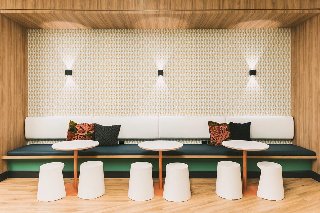 Community area with plush lounge benches, tables, and additional stool seating at The May.