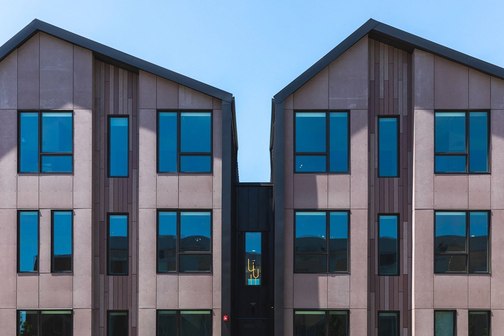 Two identical buildings with brown and beige facades and blue sky in the background.