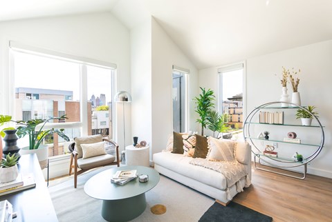 A living room with a white couch and a glass coffee table.