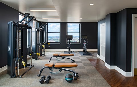 The Stott fitness center with a variety of equipment including a squat rack, bench, and weights.