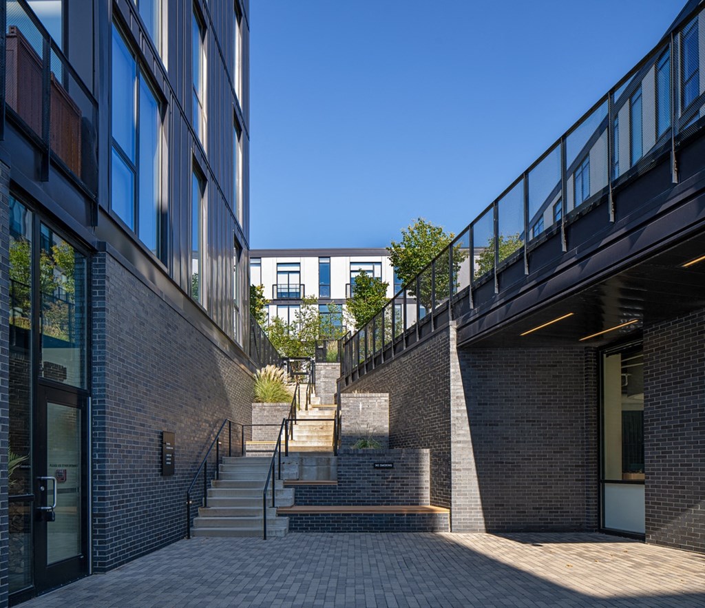 a set of stairs between two brick buildings with a blue sky in the background