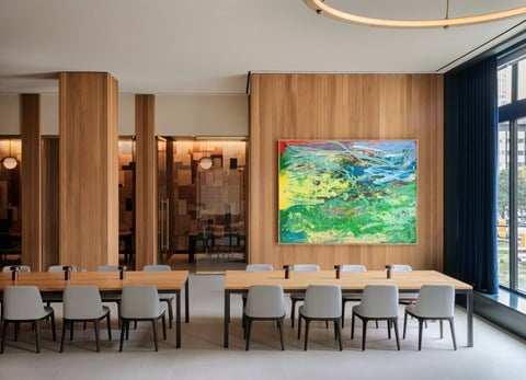 a shared amenity conference room table and chairs and a painting on the wall
