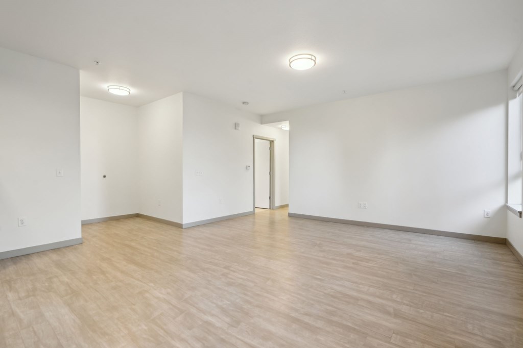 A room with wooden flooring and a door in the middle.