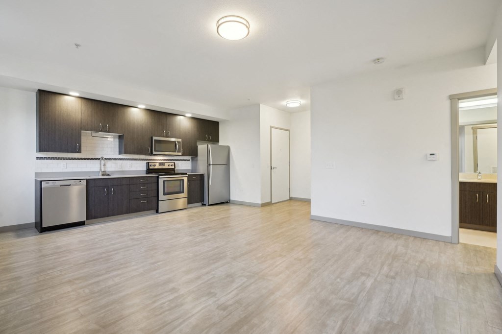 A kitchen with a refrigerator, oven, and microwave.