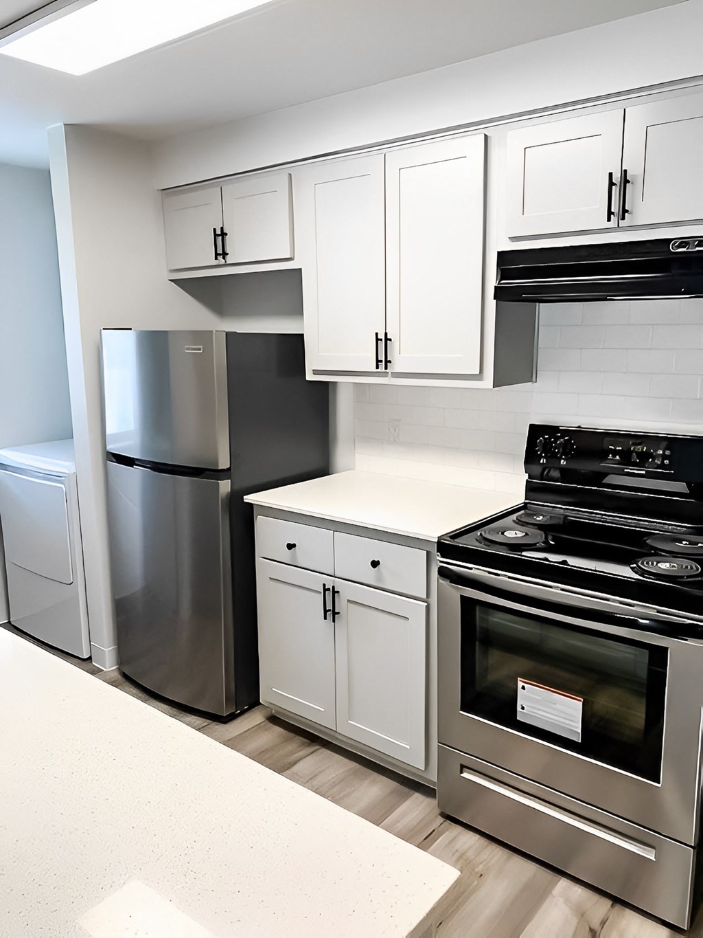 A modern kitchen with stainless steel appliances and white cabinets.