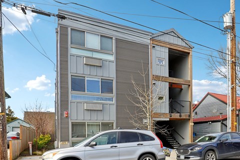 A grey building with a car parked in front.
