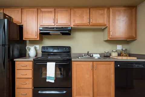 A kitchen with wooden cabinets and black appliances.