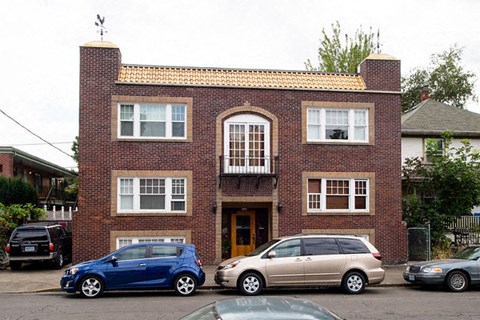 A blue car is parked in front of a brick building.